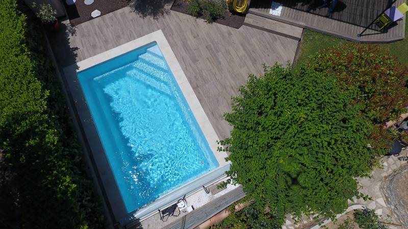 piscine vue par dessus en drone avec carrelage effet bois et margelle ton pierre