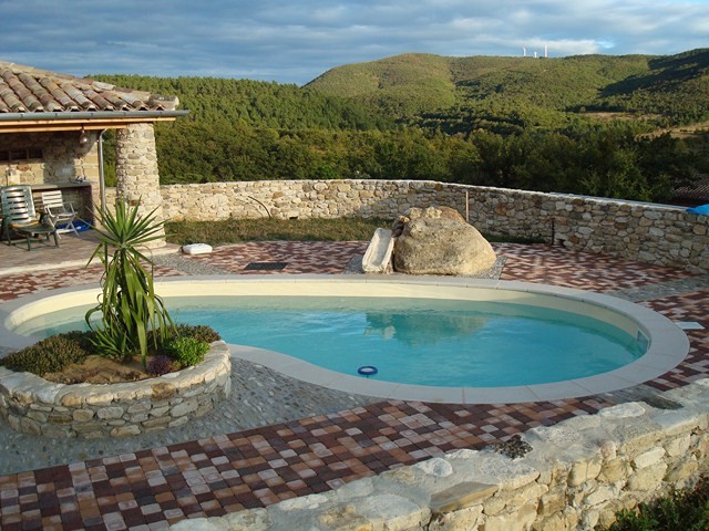piscine en forme de haricot installée près des montagnes varoises avec un sol en pavé autoblocants